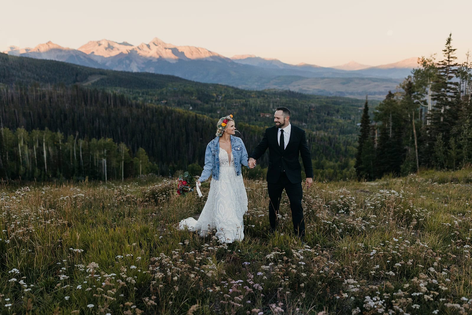 A couple walks at the top of the ski lift in Telluride after their first look on their wedding day.