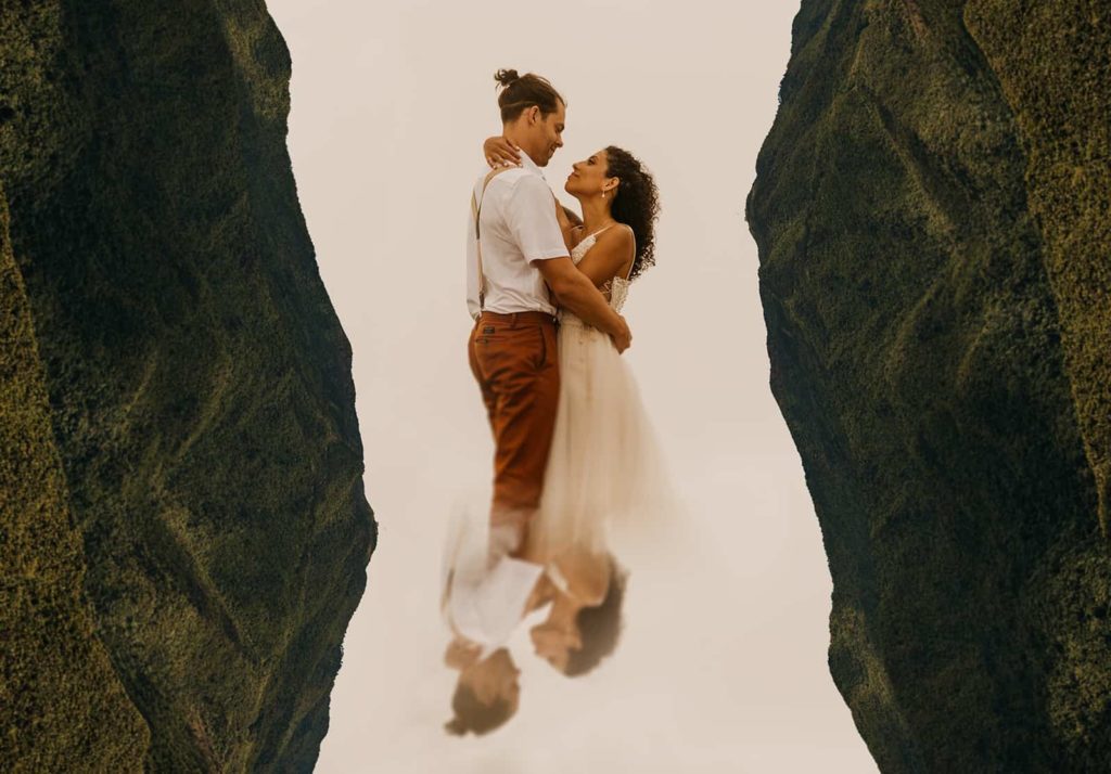 A couple stares at each other longingly with mountains surrounding them. 