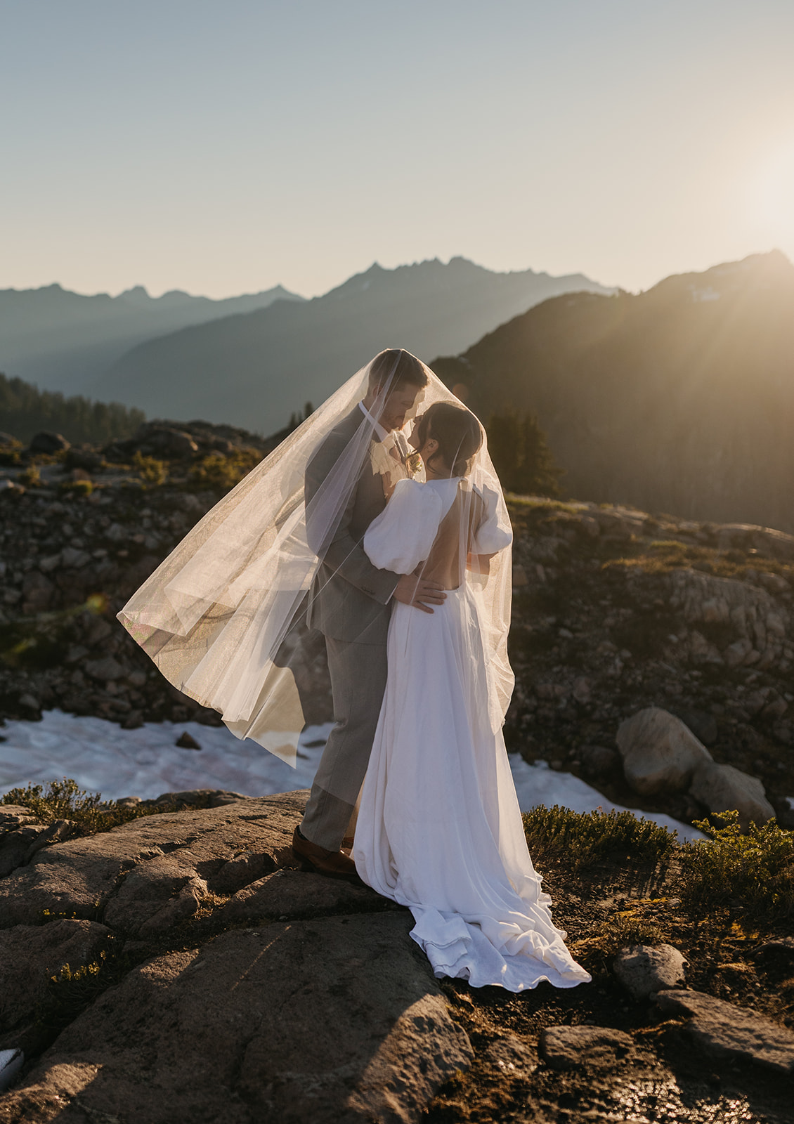 A couple stands in the sun under the brides veil together on their wedding day at Mt Baker.