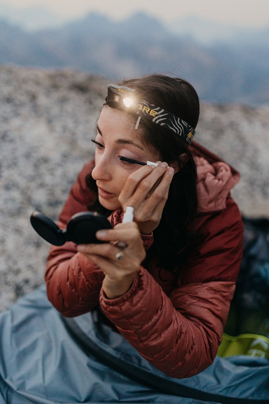 Someone doing her makeup while in a sleeping bag