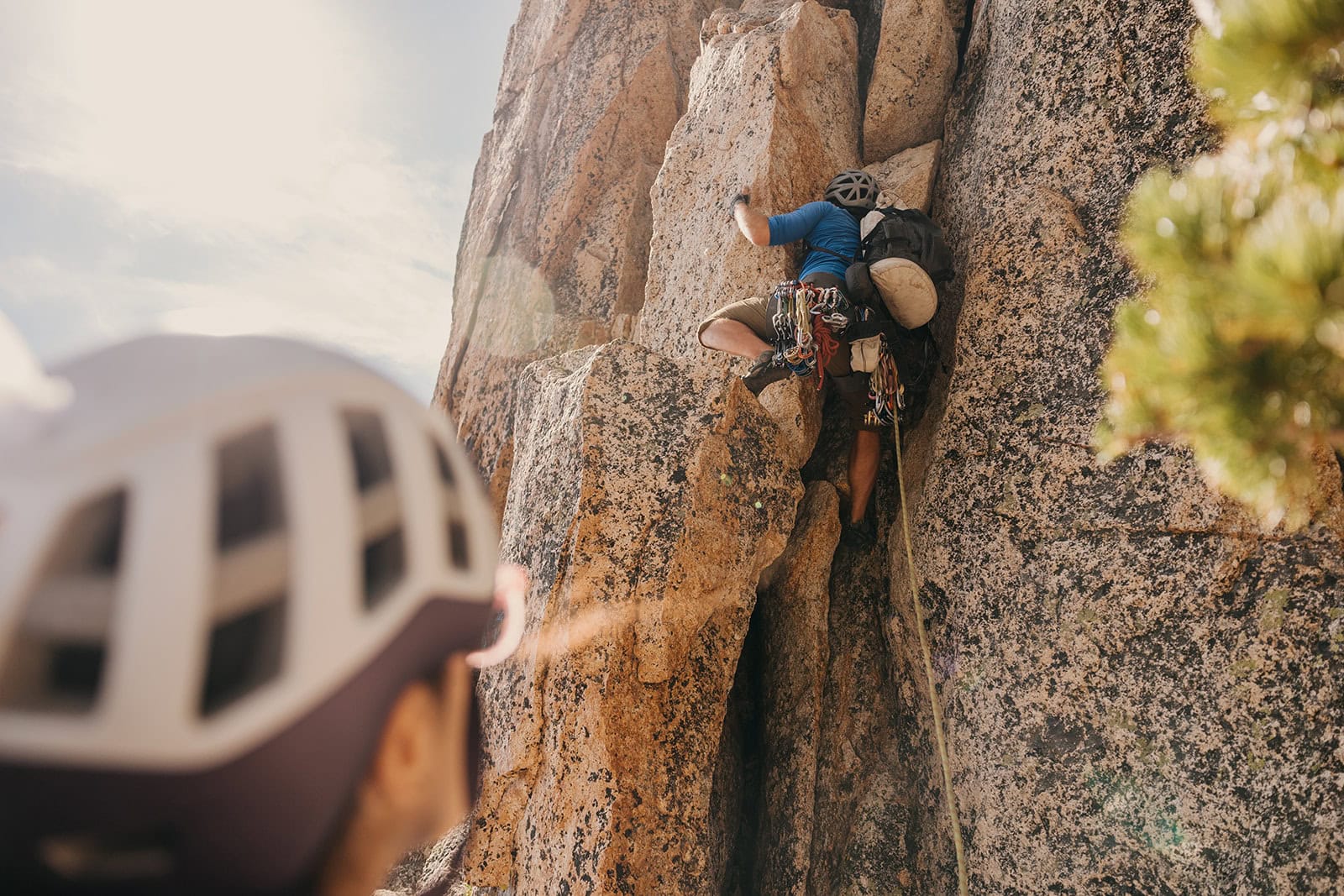 Someone belaying their partner up the pitch of a rock climb