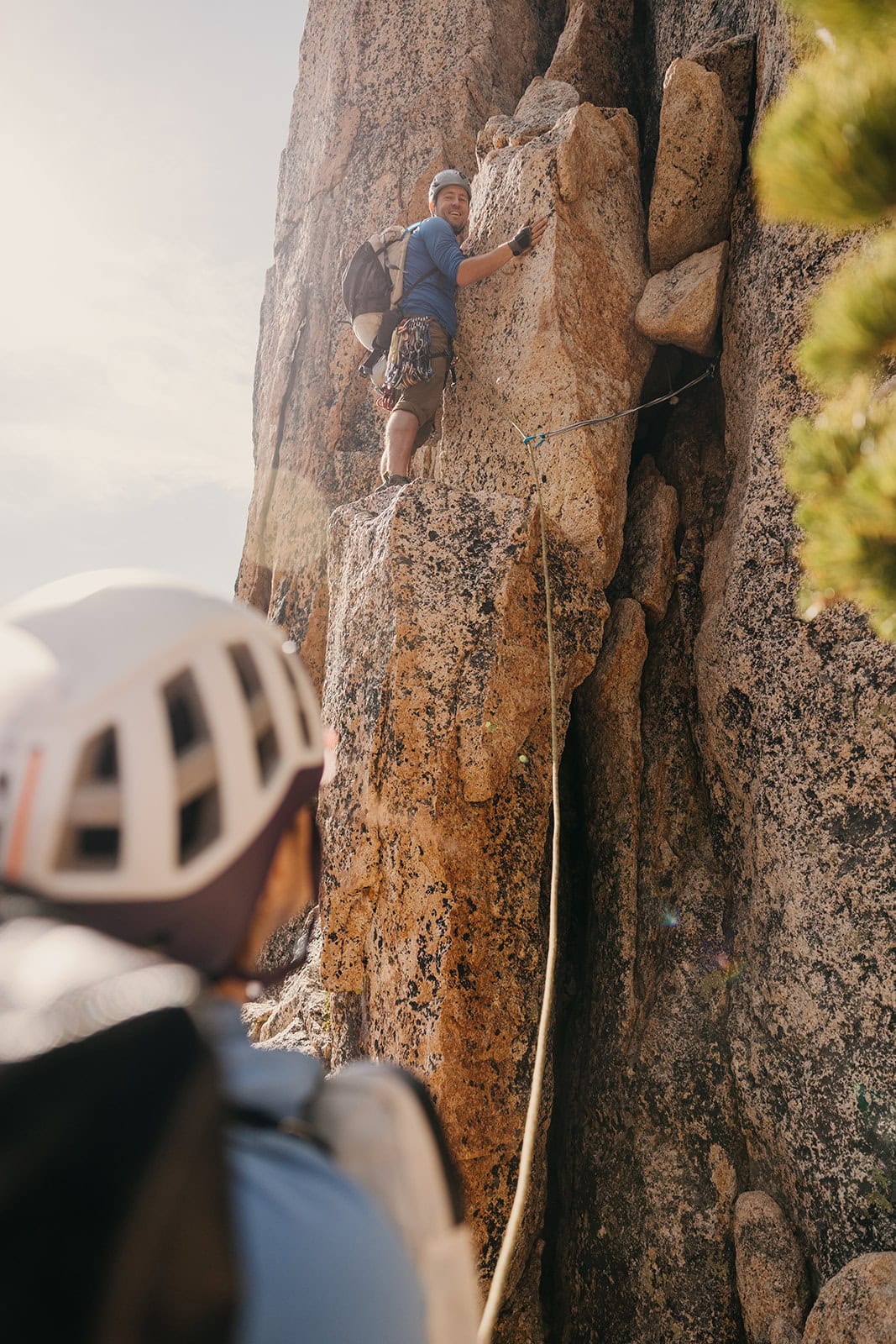 Someone belaying their partner up the pitch of a rock climb