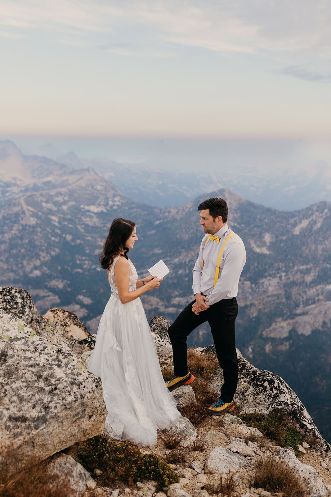 A bride reads her vows standing on top of liberty bell mountain.