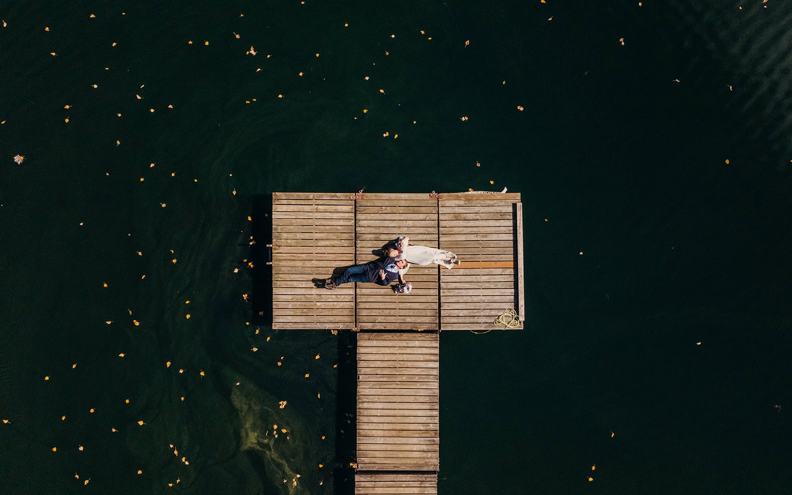A couple lays on a boat dock in the sunshine during their private picnic.