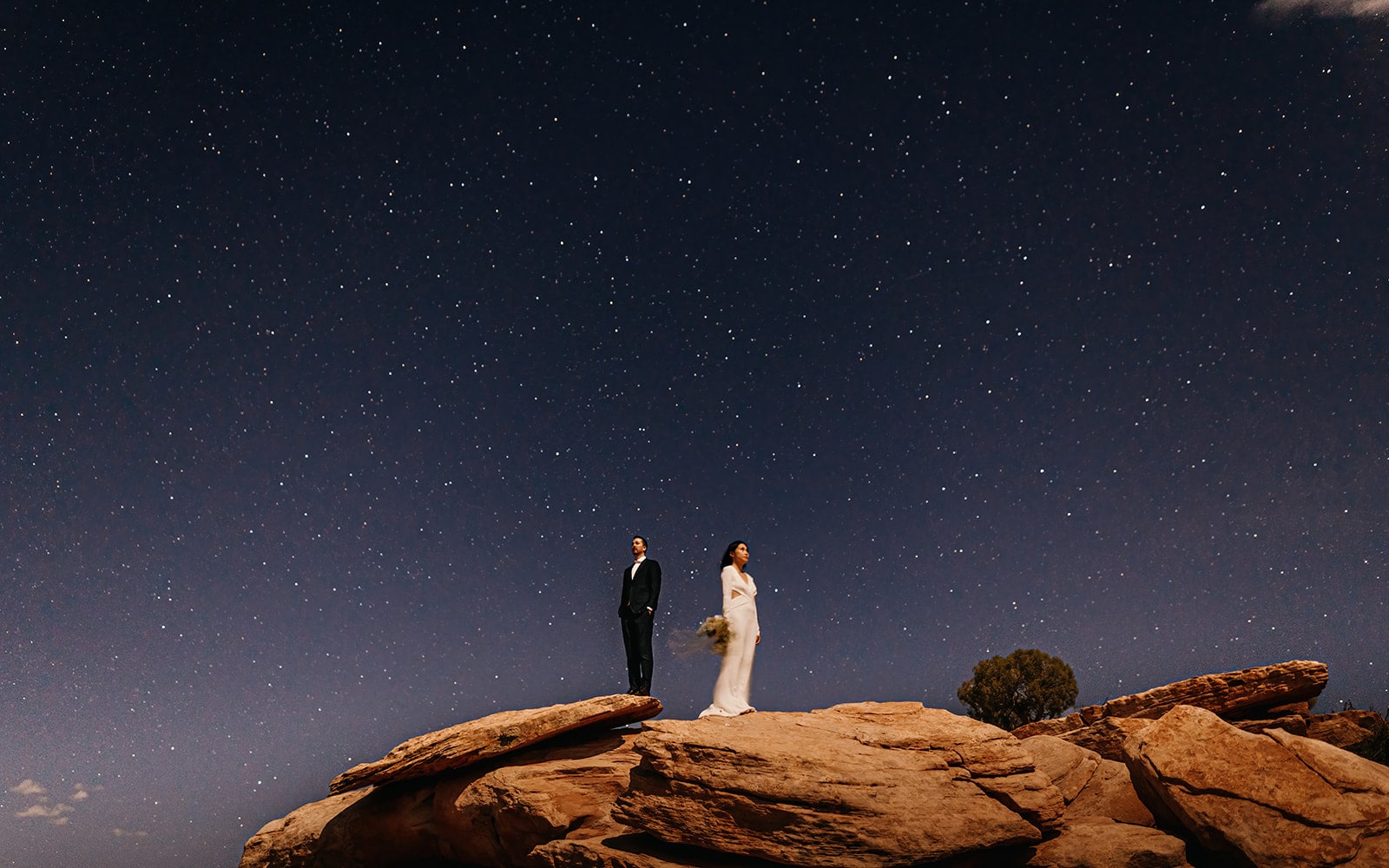A couple stands under the stars at the end of their wedding day at Dead Horse Point State Park.