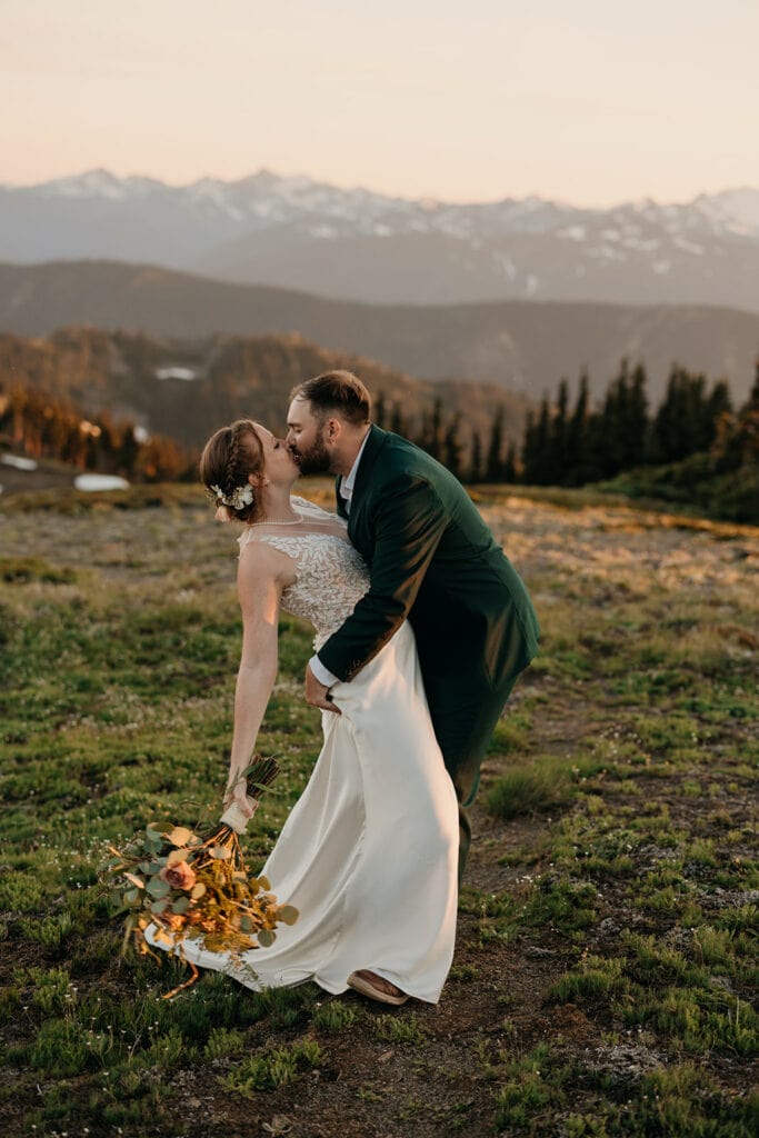 A groom kisses his bride on the trail at sunset in the mountains in Olympic National Park.