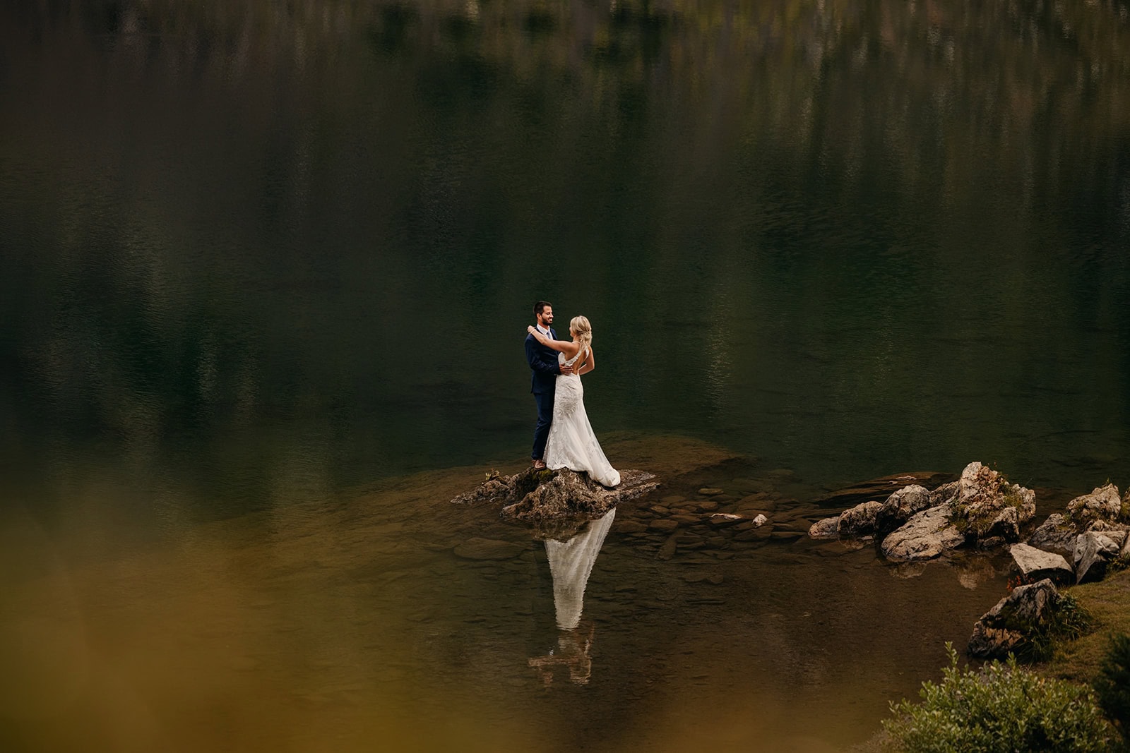 A couple holds each other in a romantic setting in the mountains.