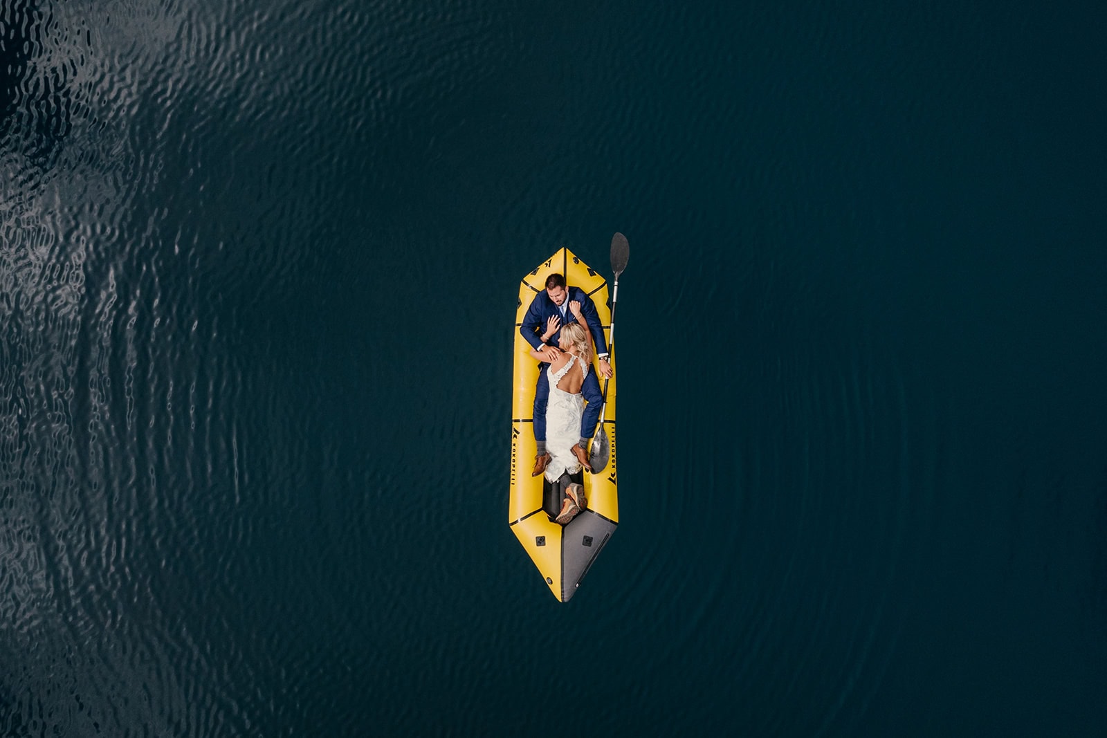 A couple cuddles up together on a kokopelli on their wedding day lakeside.