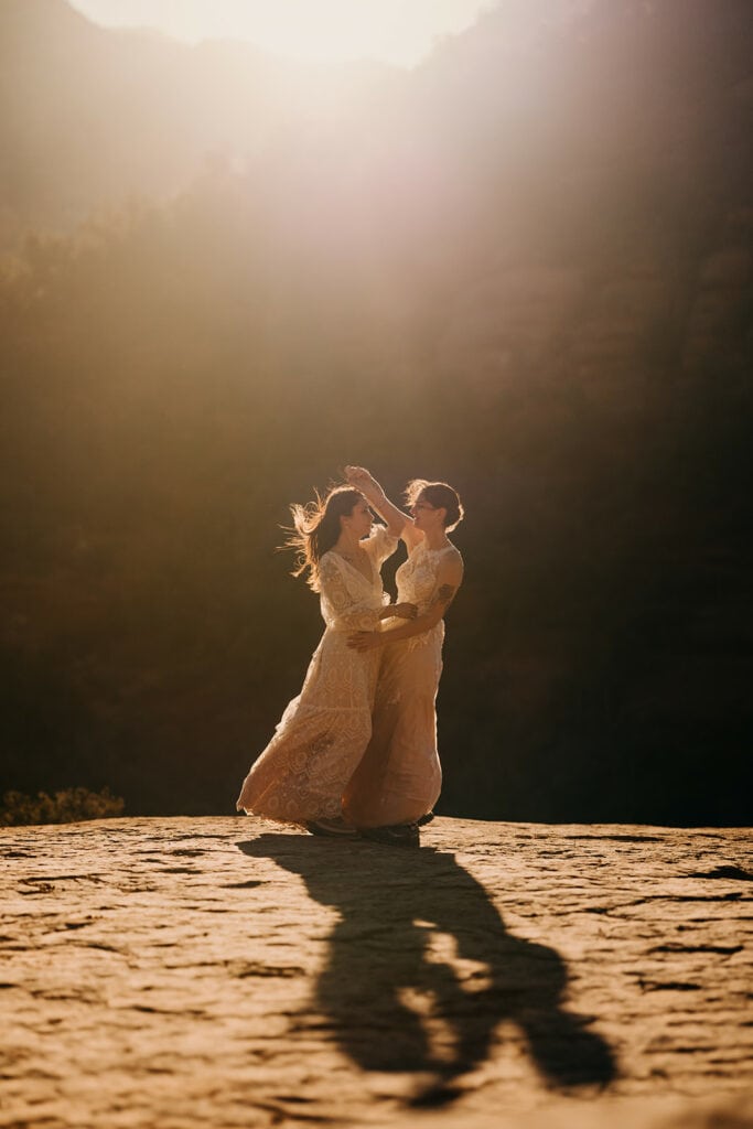 Two brides dance in the sunlight among the red rocks.