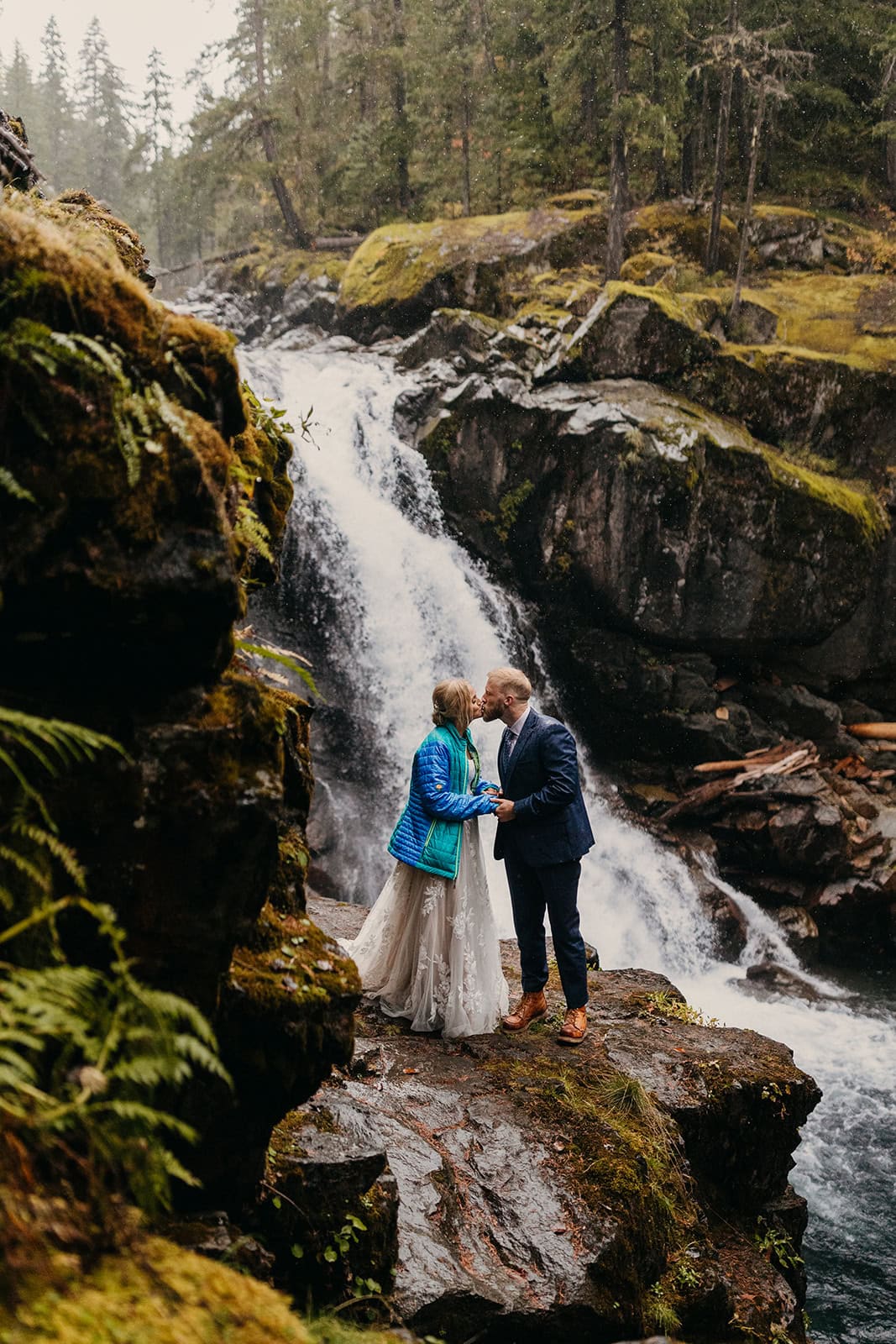 A couple shares a kiss at a popular waterfall in Mt Rainier
