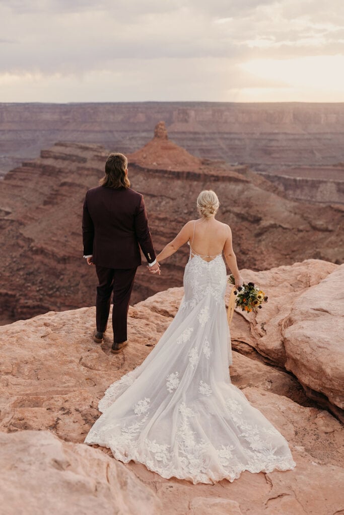 A bride and groom stand together at Dead Horse Point at Sunset