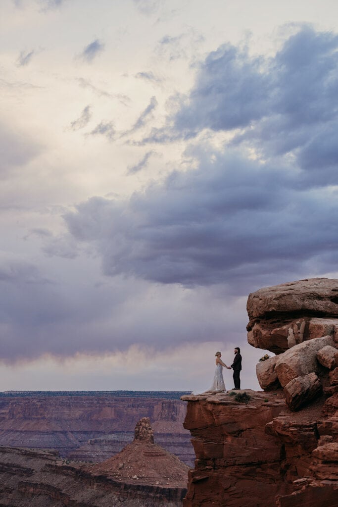 A bride and groom stand together at Dead Horse Point at Sunset