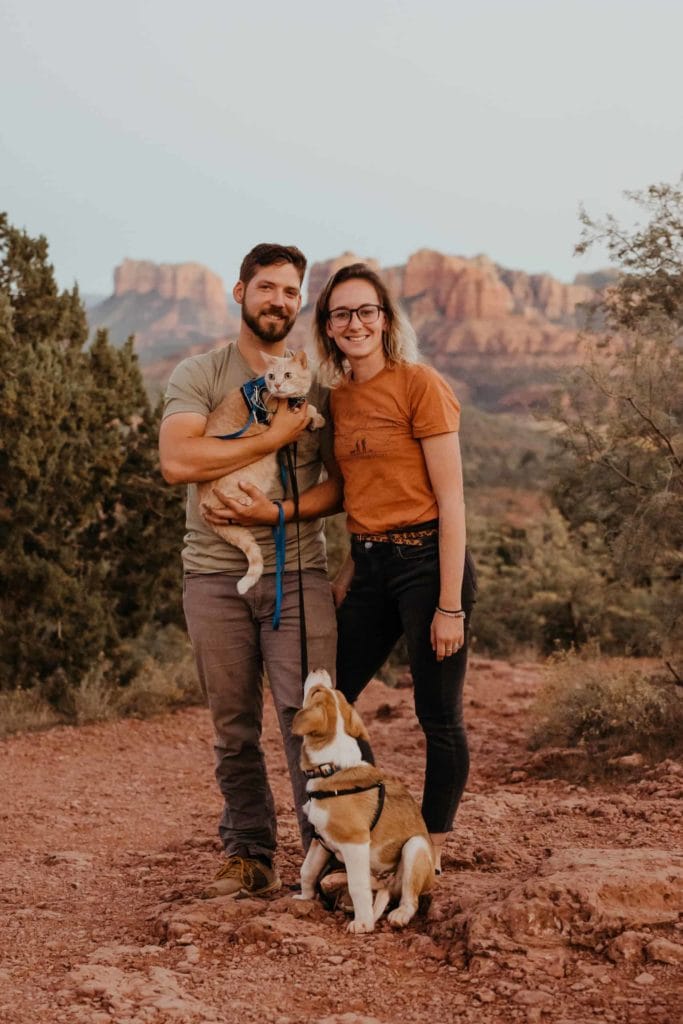 a man and woman stand together with their pets in Sedona.
