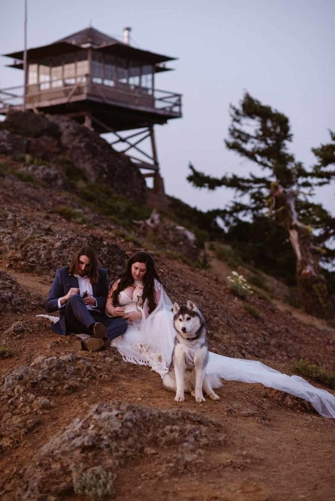A bride and groom write their vows during blue hour by a fire tower.